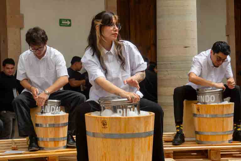 Participantes del performance RE/vuelta haciendo percusiones con barriles de madera para elaborar nieve artesanal en la Alhóndiga de Granaditas.